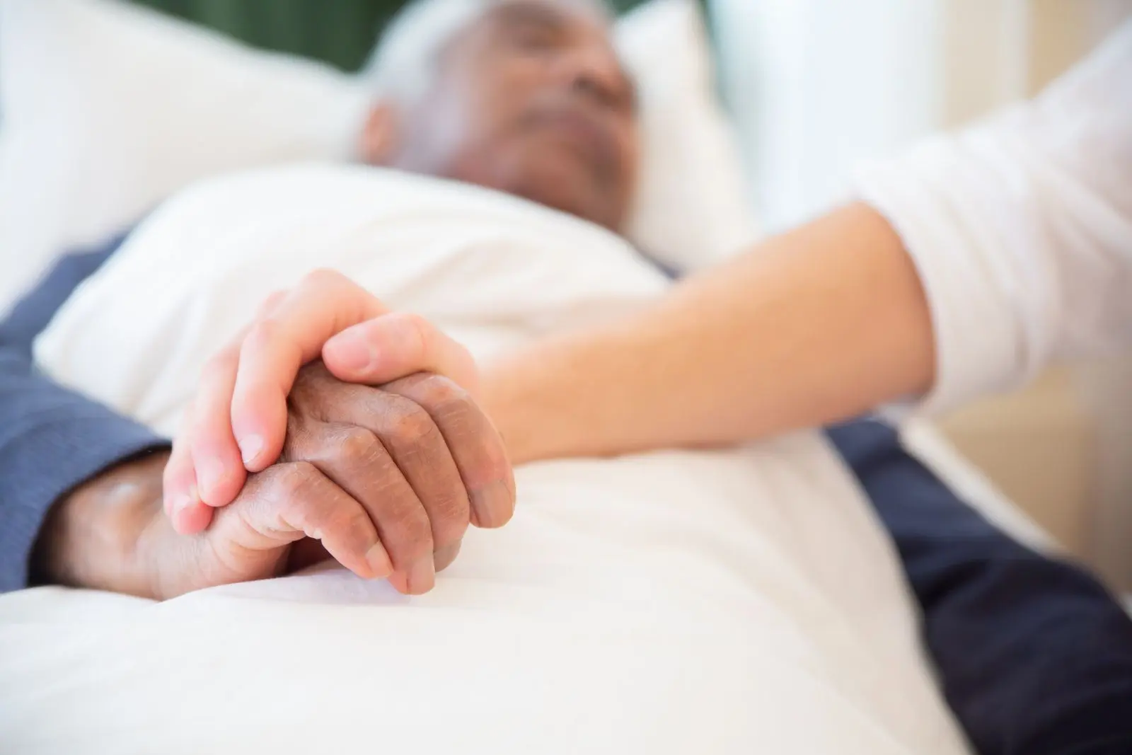 Une main jeune tenant la main d’une personne âgée
